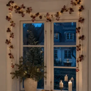 Lichterkette mit roten Beeren und Zapfen