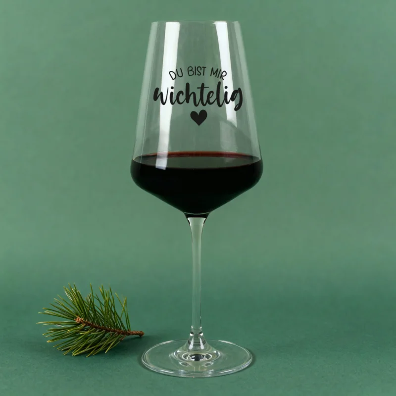 Weihnachts-Weinglas von Leonardo mit Spruch „Du bist mir wichtelig“ und Herz, auf grünem Hintergrund mit Tannenzweig
